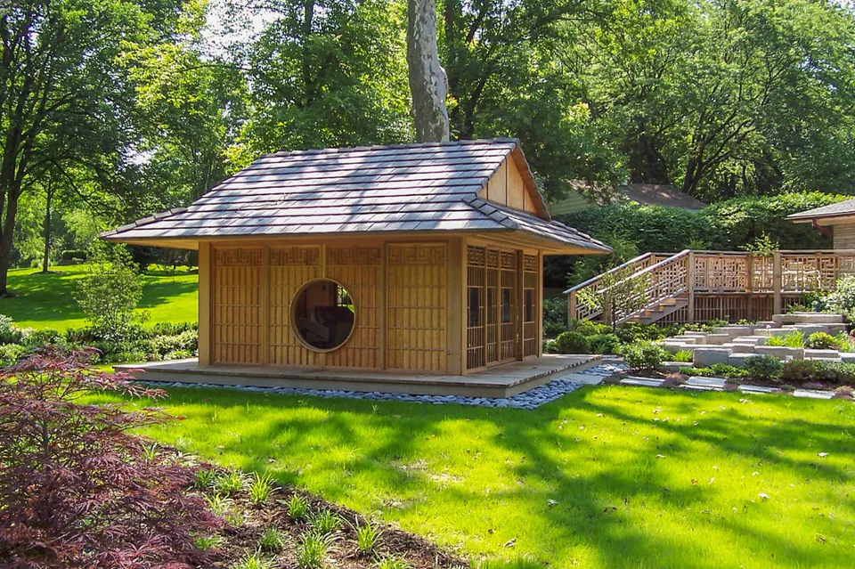 Wood garden pavilion with screen panels and surrounding ornamental planting